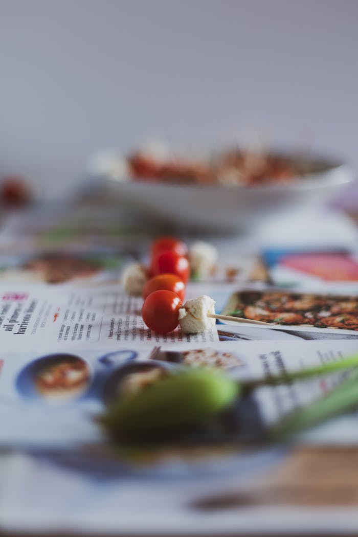 Artistic close-up shot of cherry tomatoes and cauliflower skewered and placed on newspapers.
