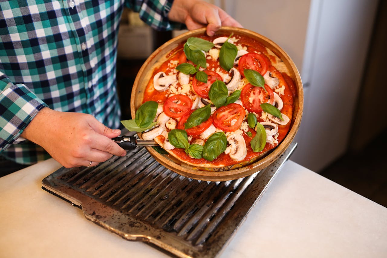 A delicious homemade pizza topped with fresh basil, tomatoes, and mushrooms, ready for baking.