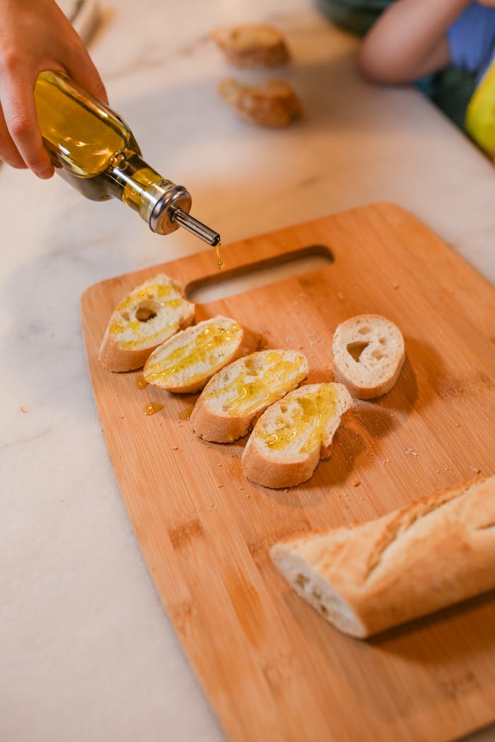 services-02 Close-up of sliced baguette being drizzled with olive oil, ideal for bruschetta.