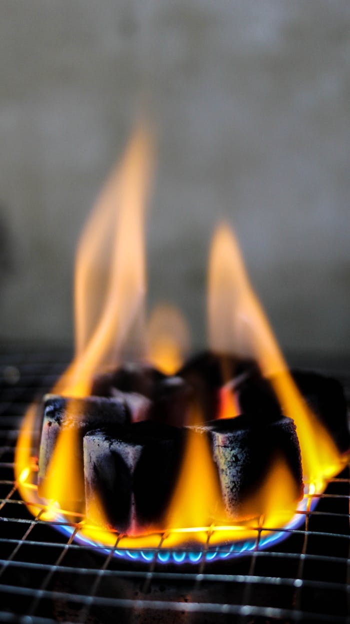 Intense flames rising from charcoal cubes on a grill, perfect for BBQ or outdoor grilling scenes.